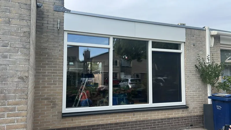Groot wit kunststof raam in een lichte gevel