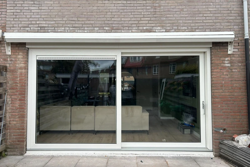 Brede witte schuifpui in een bakstenen achtergevel