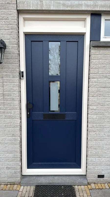 Donkerblauwe voordeur met glasstroken in een witte gevel